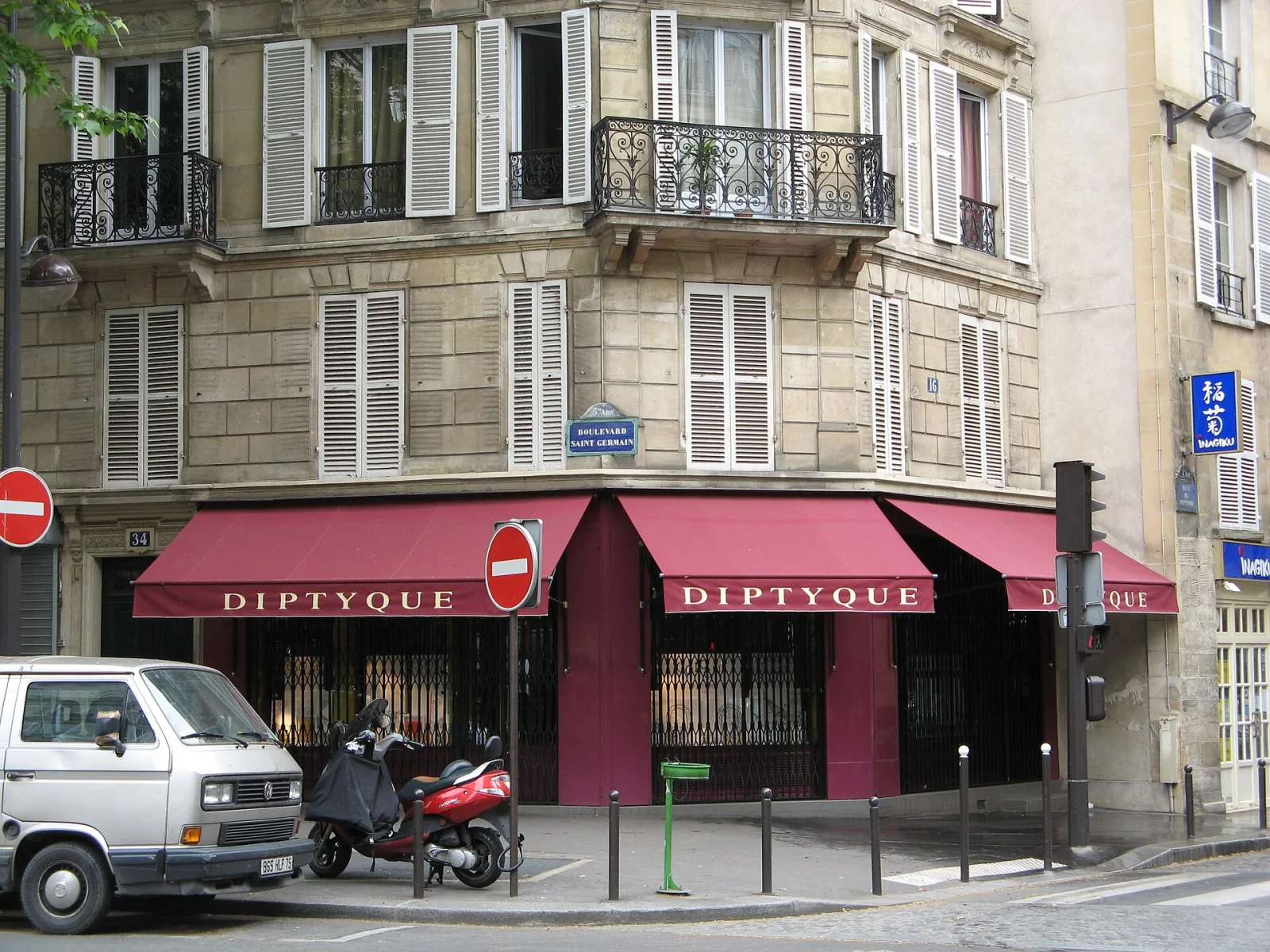 Facciata del negozio Diptyque in Boulevard Saint Germain a Parigi con tende rosse e finestre con persiane bianche.