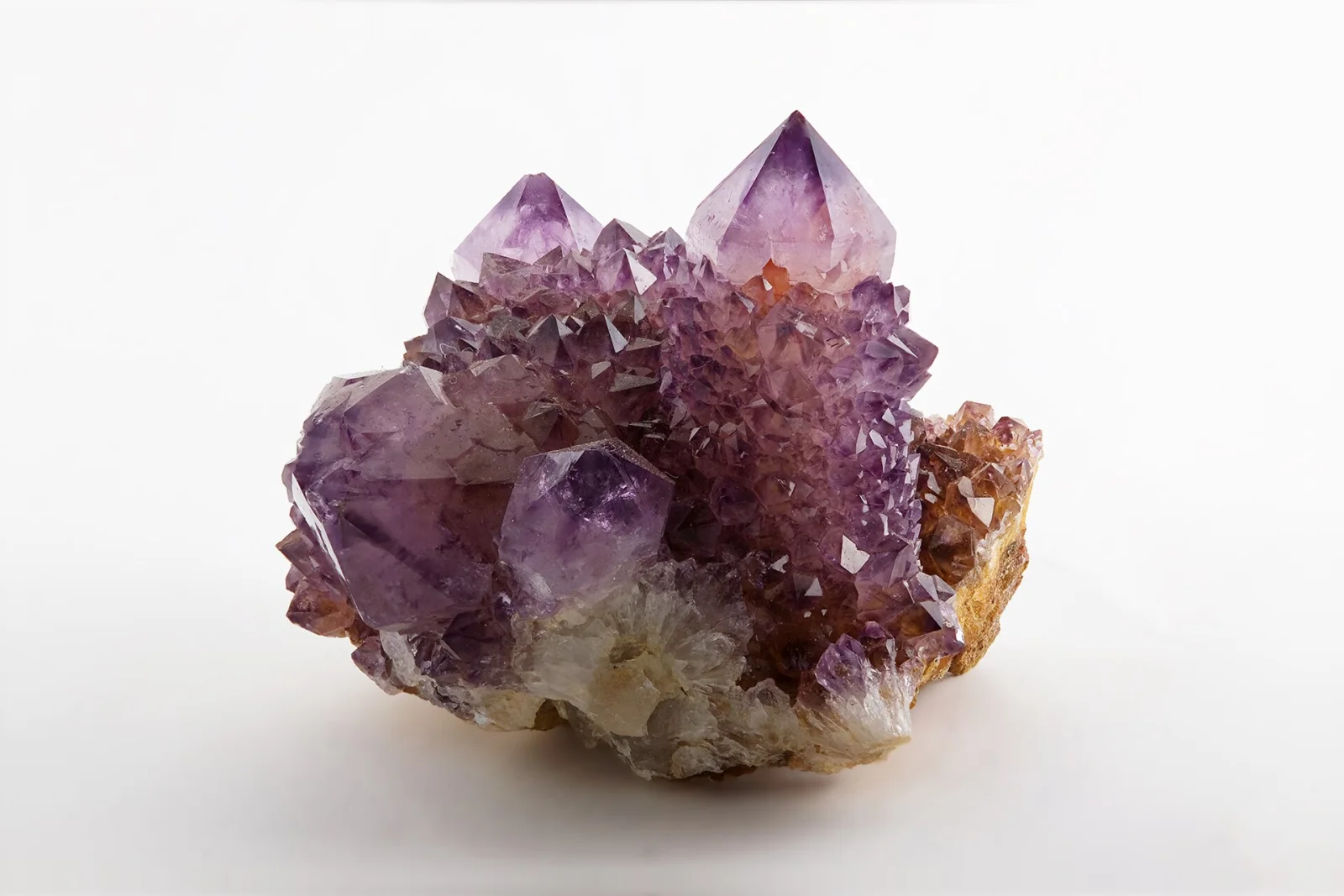 Campione di ametista di Magaliesburg, Sudafrica, con cristalli viola su matrice rocciosa su sfondo bianco.