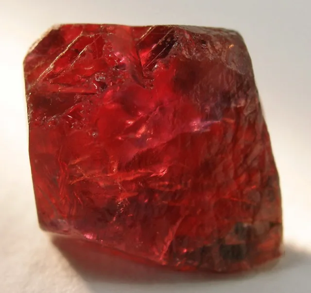 Imagen conceptual de un cristal de rubí bruto, visible en tonos rojo intenso, con superficie irregular y textura translúcida.