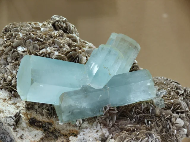 Cristales de aguamarina azul verdosa sobre un fondo de mica muscovita marrón.