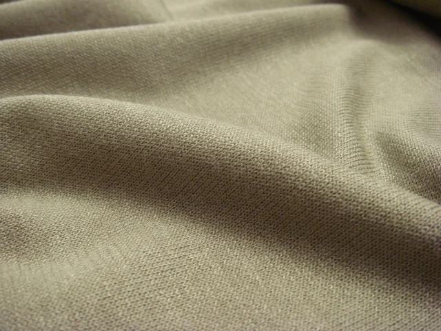 Tejido interlock jersey en primer plano, mostrando la textura y las mallas características del punto jersey.