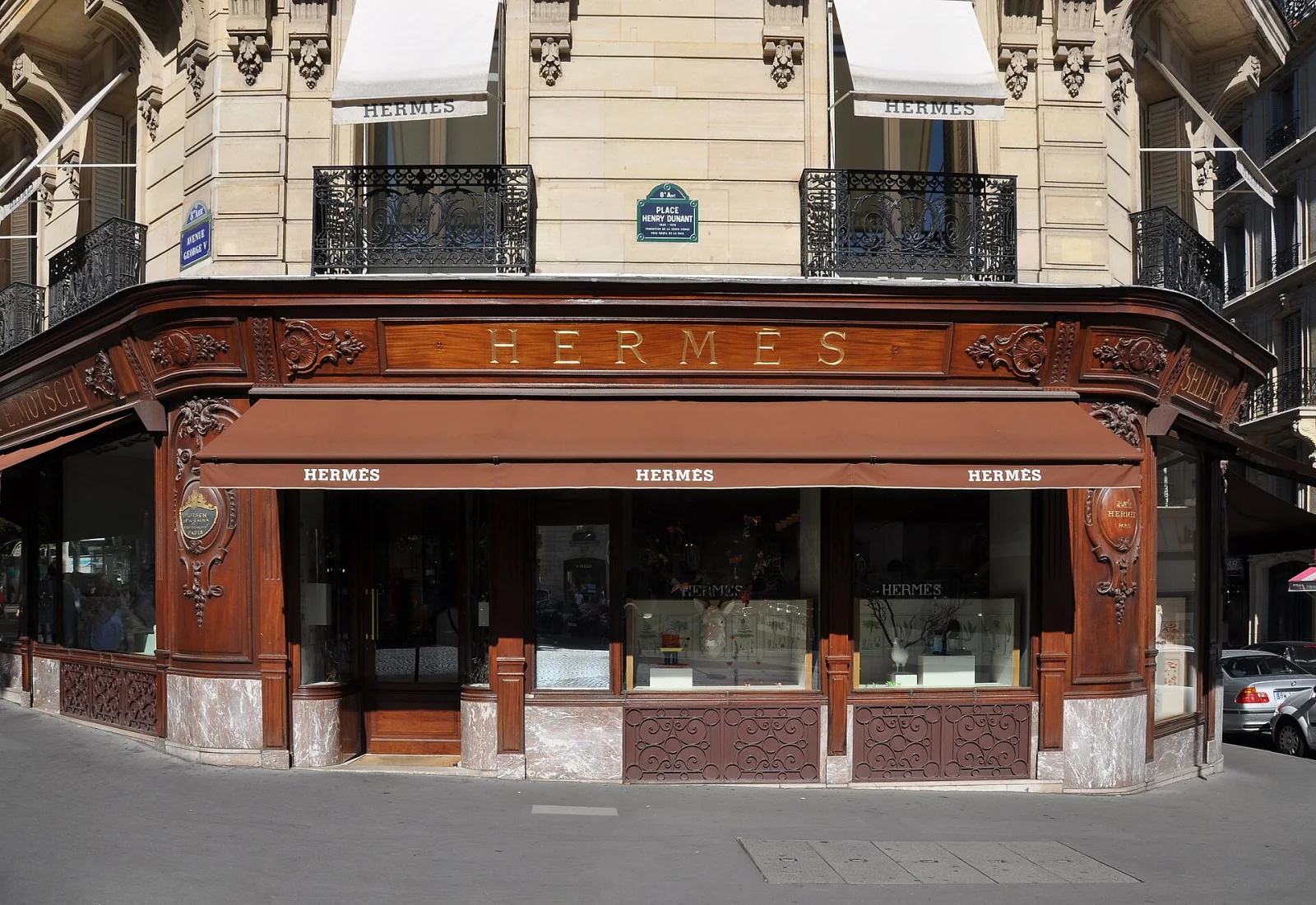 Fachada de una tienda Hermès en Avenida George V, París, con marquesinas y detalles de madera tallada.
